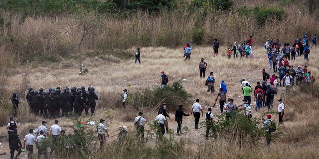 Honduran migrants, right, clash with Guatemalan soldiers and police who keep them from advancing toward the US border, on the side of the highway in Vado Hondo, Guatemala, Monday, Jan. 18, 2021. (AP Photo/Sandra Sebastian)