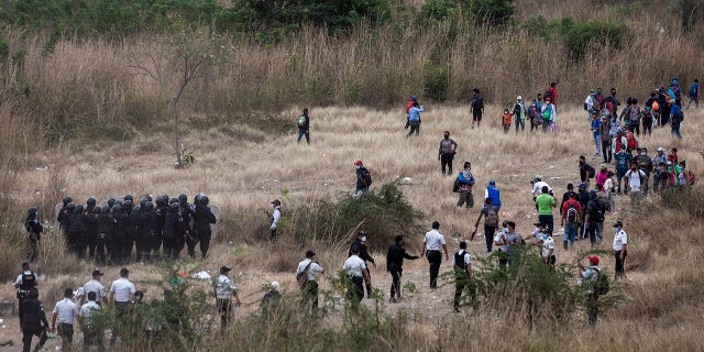 Honduran migrants, right, clash with Guatemalan soldiers and police who keep them from advancing toward the US border, on the side of the highway in Vado Hondo, Guatemala, Monday, Jan. 18, 2021. (AP Photo/Sandra Sebastian)