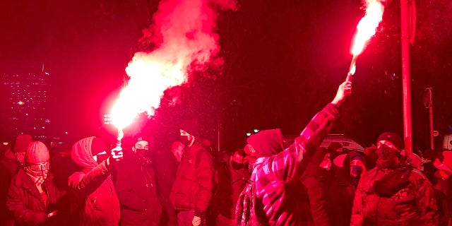 People light flares as they march near the ruling Law and Justice party headquarters in Warsaw, Poland, Wednesday Jan. 27, 2021, to protest after the country's top court on Wednesday confirmed its highly divisive ruling that will further tighten the predominantly Catholic nation's strict anti-abortion law. The Constitutional Tribunal published the justification of its decision, which means it can now be officially printed and take immediate effect. (AP Photo/Czarek Sokolowski)