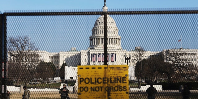 National guards are seen Wednesday, Jan. 13, 2021, on a fence that was erected to reinforce security at the Capitol in Washington.