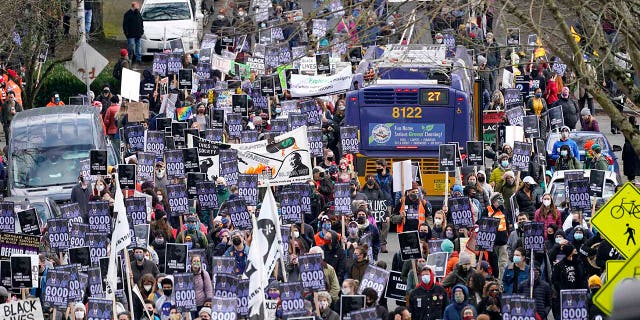 Demonstrators fill a street and march around a bus stopped in the crowd during the 39th annual Seattle MLK Jr. Day March and Rally, 星期一, 一月. 18, 2021, 在西雅图. The event celebrates the national holiday in honor of the Rev. Martin Luther King Jr.'s birthday and this year's theme was "Good trouble, necessary trouble," in honor of the words of the late Congressman John Lewis. (AP Photo/Elaine Thompson)