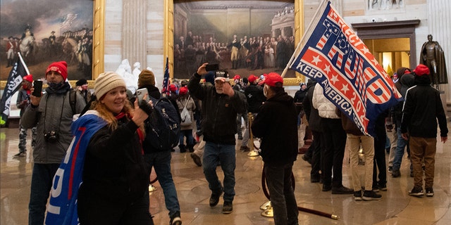 Jenny Cudd, of Midland, Texas, is seen inside the US Capitol holding her phone and draped with a Trump flag. (SAUL LOEB/AFP via Getty Images)