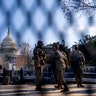 Members of the National Guard stand guard behind fencing surrounding the U.S. Capitol on Capitol Hill in Washington, Thursday, Jan. 14, 2021. (AP Photo/Andrew Harnik)