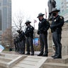 Ohio state troopers provide security at the Ohio Statehouse as armed protestors look on Sunday, Jan. 17, 2021, in Columbus, Ohio. Security was stepped up at statehouses across the U.S. after FBI warnings of potential armed protests at all 50 state capitols and in Washington, D.C.