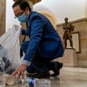 Rep. Andy Kim, D-N.J., cleans up debris and trash strewn across the floor in the early morning hours of Thursday, Jan. 7, 2021, after protesters stormed the Capitol in Washington, on Wednesday.