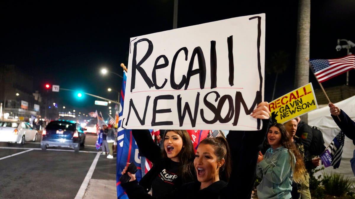 FILE: Demonstrators shout slogans while carrying a sign calling for the recall of Gov. Gavin Newsom during a protest against a stay-at-home order amid the COVID-19 pandemic in Huntington Beach, Calif. 