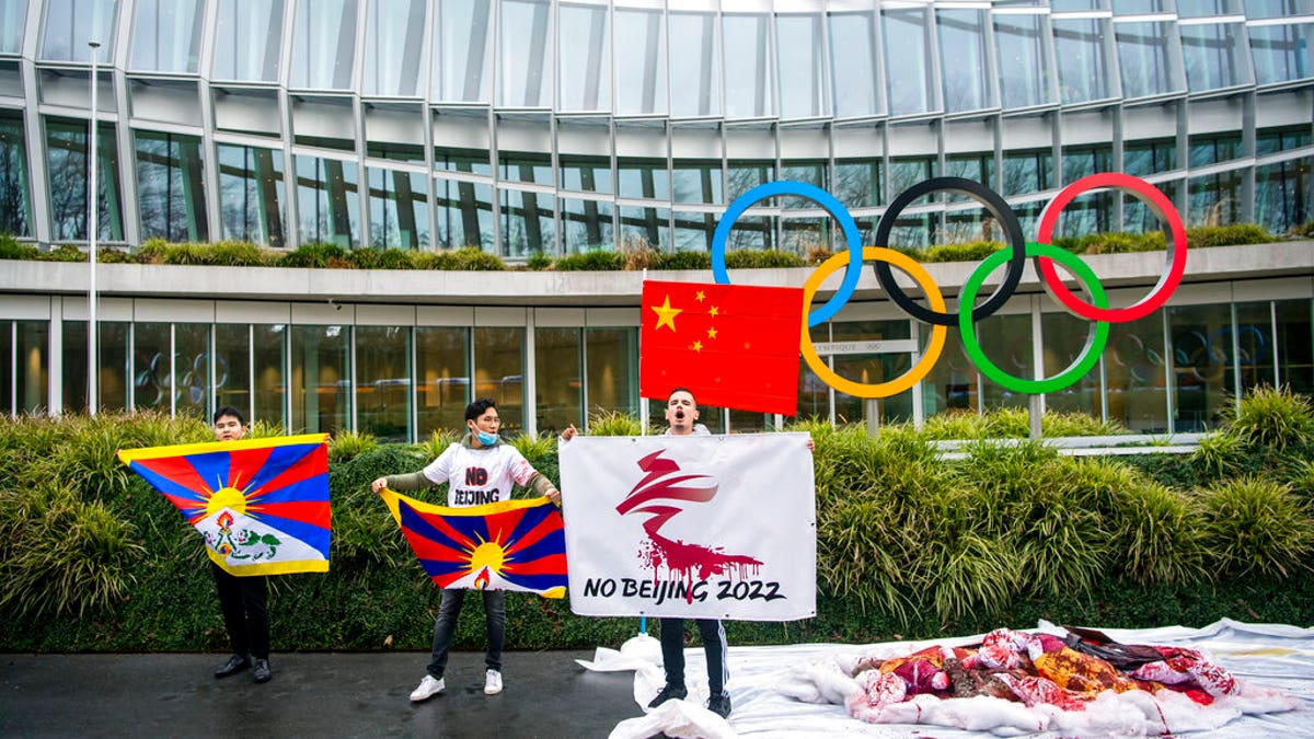 Protesters hold Tibetan flags during a protest against Beijing 2022 Winter Olympics by activists of the Tibetan Youth Association in Europe, in front of the International Olympic Committee, IOC, headquarters in Lausanne, Switzerland, Wednesday, Feb. 3, 2021. A coalition of 180 rights groups is calling for a boycott of next year's Beijing Winter Olympics tied to reported human rights abuses in China. The games are to open on February 4, 2022. (Jean-Christophe Bott/Keystone via AP)