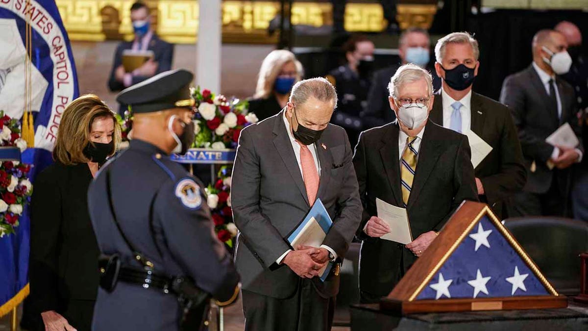 House Speaker Nancy Pelosi, left, Senate Majority Leader Chuck Schumer of New York, center, Senate Minority Leader Mitch McConnell of Kentucky, and House Minority Leader Kevin McCarthy of California, pause to pay their last respects during a ceremony memorializing U.S. Capitol Police officer Brian Sicknick, as an urn with his cremated remains lies in honor on a black-draped table at the center of the Capitol Rotunda, Wednesday, Feb. 3, 2021, in Washington. (Demetrius Freeman/The Washington Post via AP, Pool)