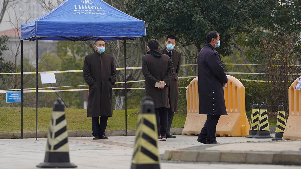 Security personnel watch a checkpoint into the cordoned off area where a World Health Organization team is staying at a hotel in central China's Hubei province on Thursday, Feb. 4, 2021. The WHO team is investigating the origins of the coronavirus pandemic in the province. (AP Photo/Ng Han Guan)