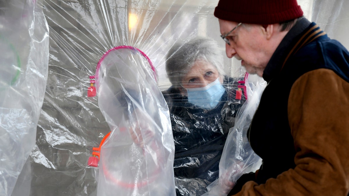 Lynda Hartman, 75, visits her 77-year-old husband, Len Hartman, in a "hug tent" set up outside the Juniper Village assisted living center in Louisville, Colorado, on Wednesday. (AP Photo/Thomas Peipert)