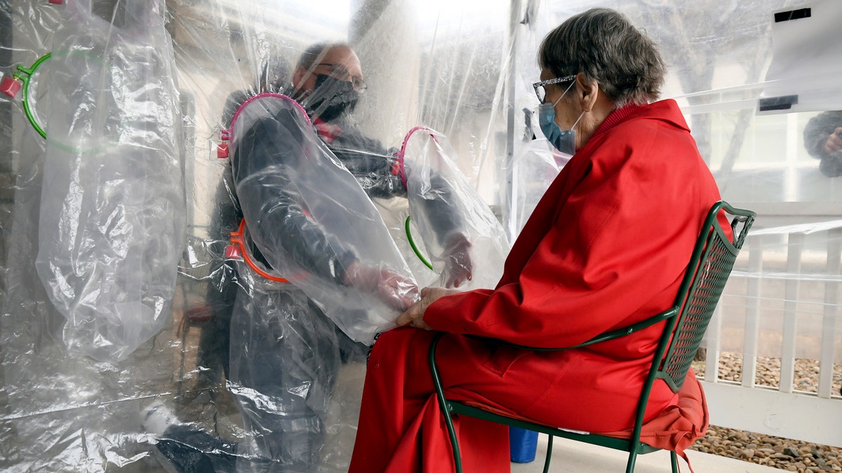 Gregg MacDonald holds hands with his 84-year-old mother, Chloe MacDonald, at the "hug tent" outside the Juniper Village assisted living center in Louisville, Colorado. (AP Photo/Thomas Peipert)