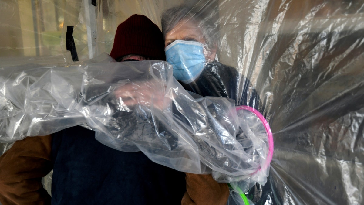 Lynda Hartman embraces her husband, Len Hartman, who suffers from dementia in a "hug tent." He has been living at the center for about a year, and the couple had not had any physical contact for at least eight months. (AP Photo/Thomas Peipert)