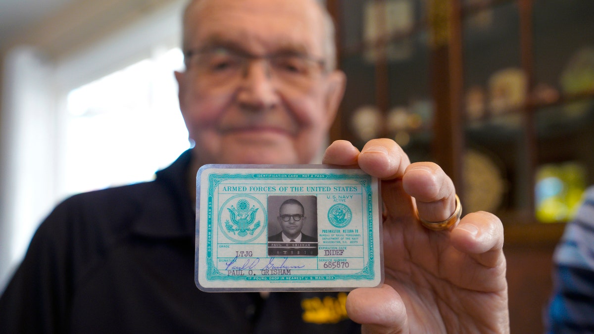 Paul Grisham holds his 1968 Navy ID card, which was found inside his wallet. (Nelvin C. Cepeda/The San Diego Union-Tribune via AP)