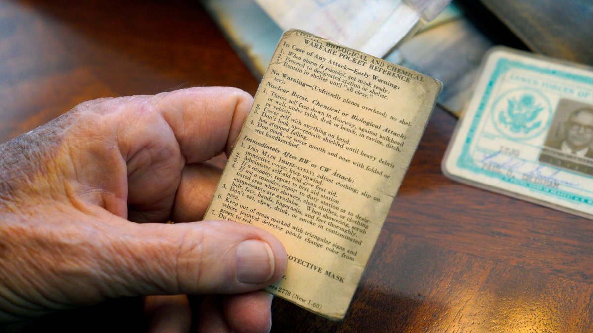 Paul Grisham holds one of the items that was found inside his wallet, an "Atomic, Biological, and Chemical Warfare Pocket Reference." (Nelvin C. Cepeda/The San Diego Union-Tribune via AP)