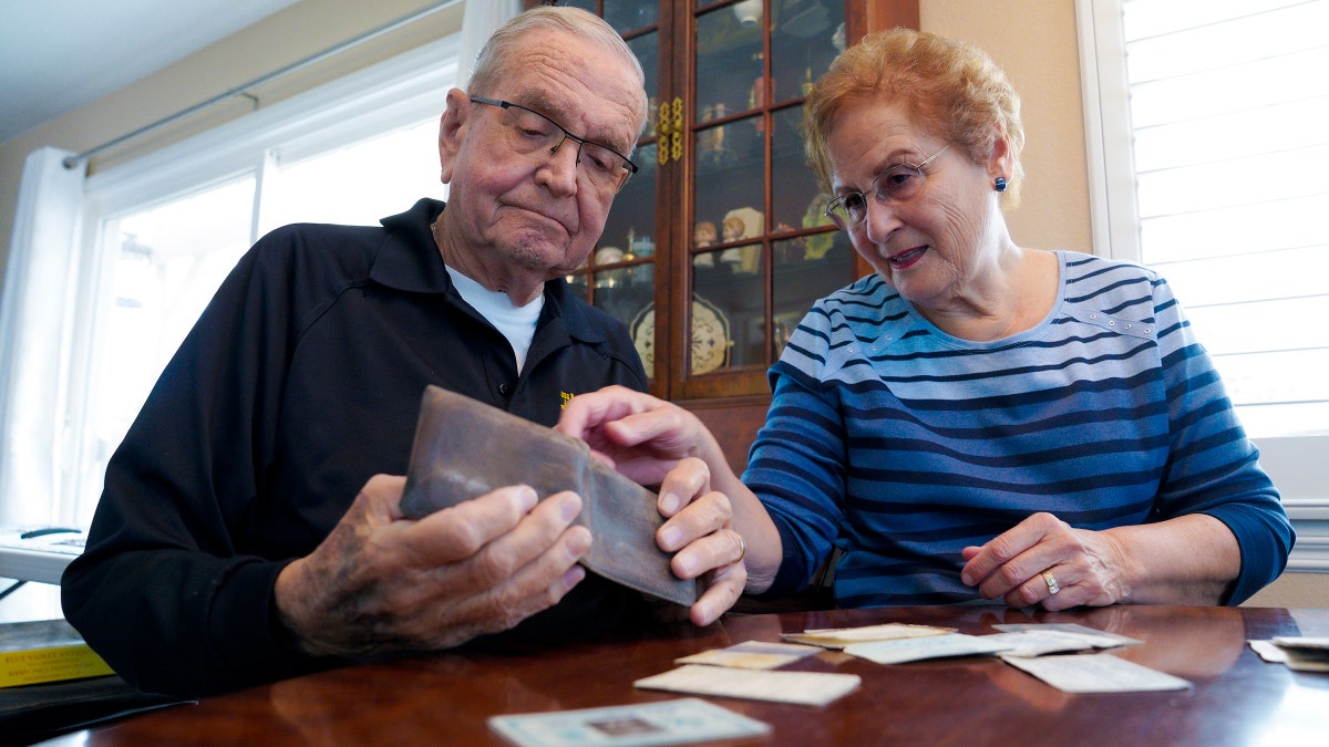 Paul Grisham and his wife Carole Salazar look over his wallet and the items that were inside when he lost the wallet back in 1968. (Nelvin C. Cepeda/The San Diego Union-Tribune via AP)