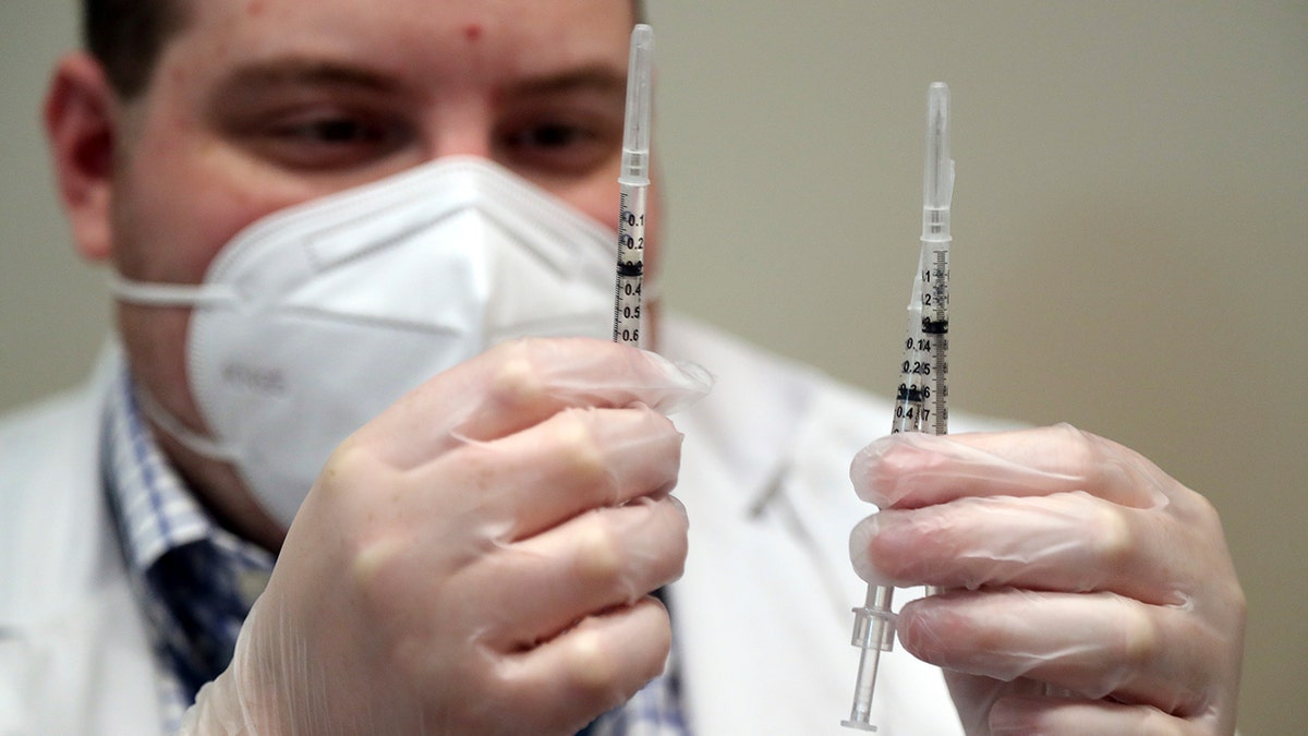 Walgreens pharmacist Brandon Berger checks syringes before administering second doses of the Pfizer COVID-19 vaccine to seniors at John Knox Village, Tuesday, Feb. 9, 2021, in Pompano Beach, Fla. (Amy Beth Bennett/South Florida Sun-Sentinel via AP)