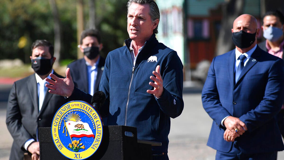 California Gov. Gavin Newsom, center, gestures in front of local officials while speaking about COVID-19 vaccines at the Fresno Fairgrounds, Wednesday, Feb. 10, 2021, in Fresno, Calif.