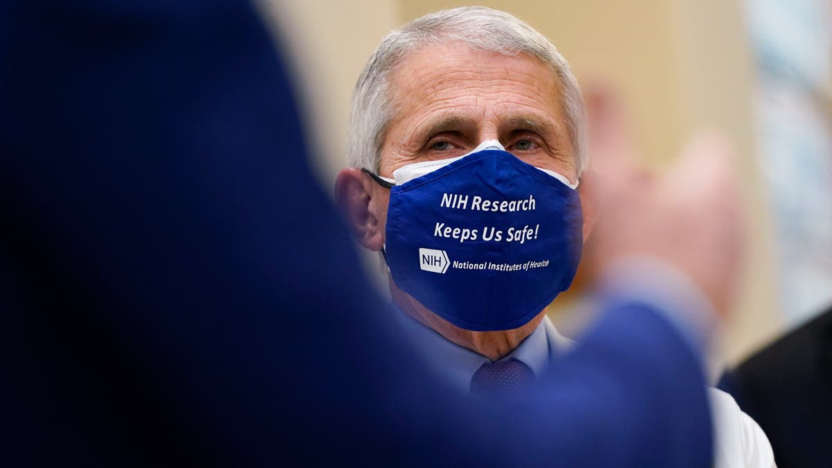 Dr. Anthony Fauci, director of the National Institute of Allergy and Infectious Diseases, listens as President Joe Biden speaks during a visit at the Viral Pathogenesis Laboratory at the National Institutes of Health (NIH), Thursday, Feb. 11, 2021, in Bethesda, Md. (AP Photo/Evan Vucci)