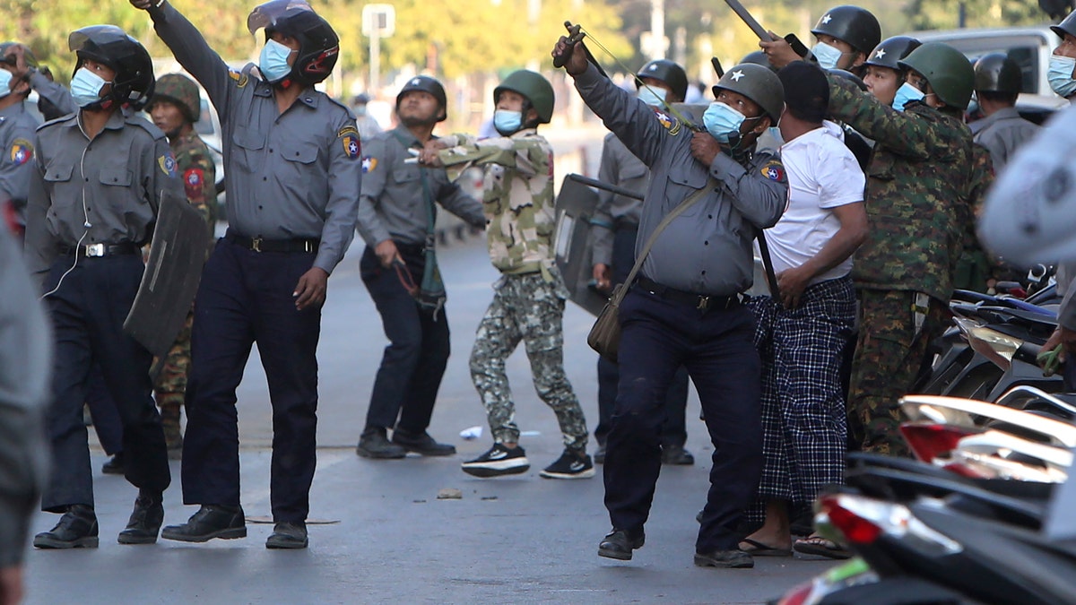 A policeman aims a slingshot towards an unknown target during a crackdown on anti-coup protesters holding a rally in front of the Myanmar Economic Bank in Mandalay, Burma on Monday, Feb. 15, 2021. (AP Photo)