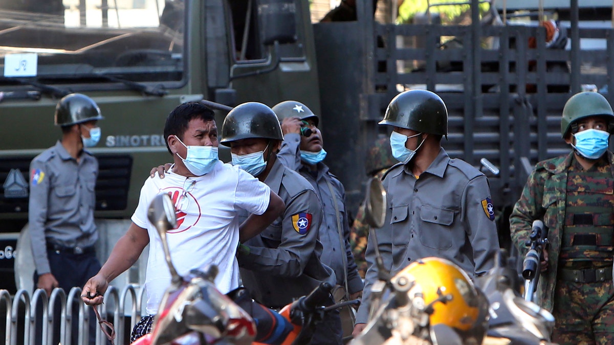 A man is held by police during a crackdown on anti-coup protesters holding a rally in front of the Myanmar Economic Bank in Mandalay, Burma on Monday, Feb. 15, 2021. (AP Photo)