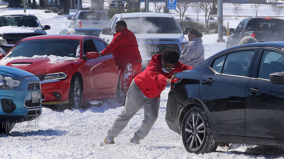 People push a car free after spinning out in the snow Monday, Feb. 15, 2021 in Waco, Texas. (Associated Press)