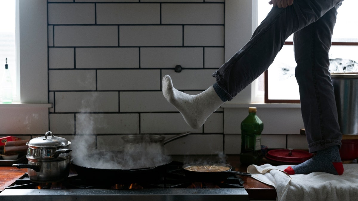 Jorge Sanhueza-Lyon stands on his kitchen counter to warm his feet over his gas stove Tuesday, Feb. 16, 2021, in Austin, Texas.  (AP Photo/Ashley Landis)