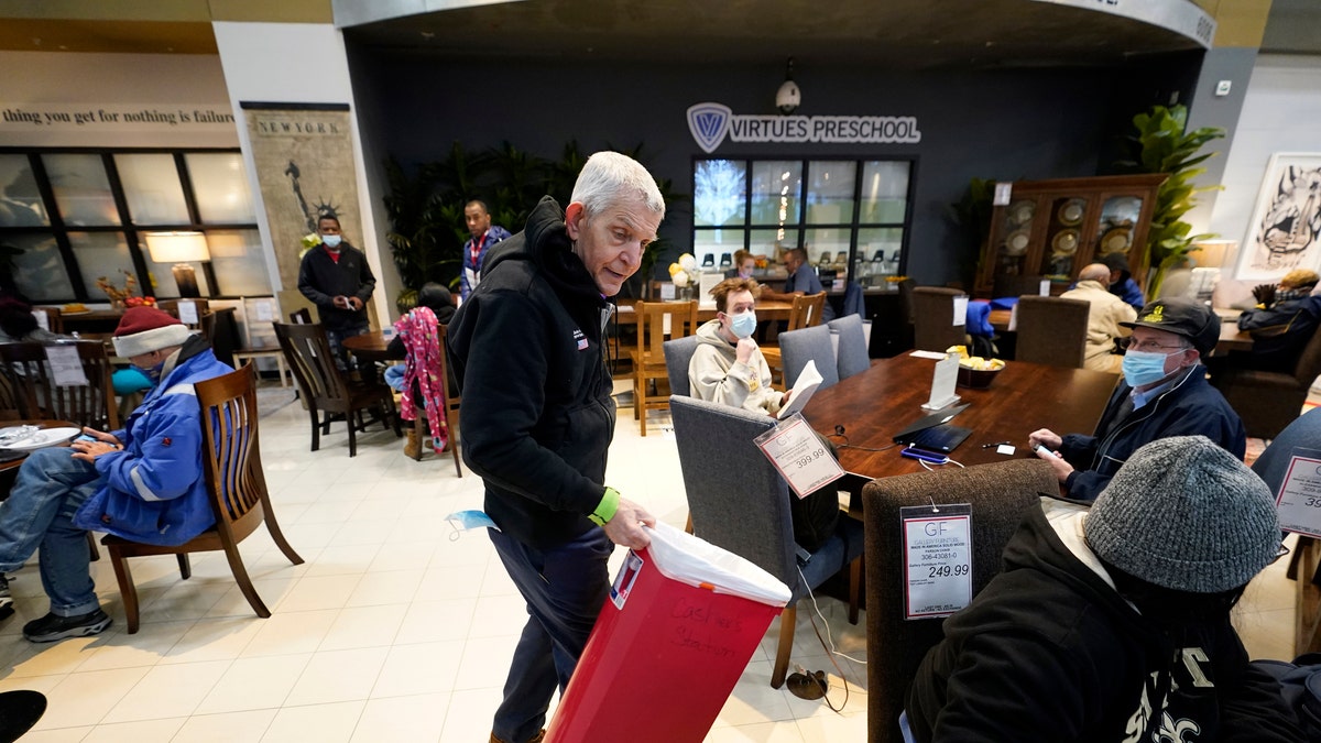 Owner Jim McIngvale collects trash inside his Gallery Furniture store, which opened as a shelter Wednesday, Feb. 17, 2021, in Houston. Millions in Texas still had no power after a historic snowfall and single-digit temperatures created a surge of demand for electricity to warm up homes unaccustomed to such extreme lows, buckling the state's power grid and causing widespread blackouts. (AP Photo/David J. Phillip)