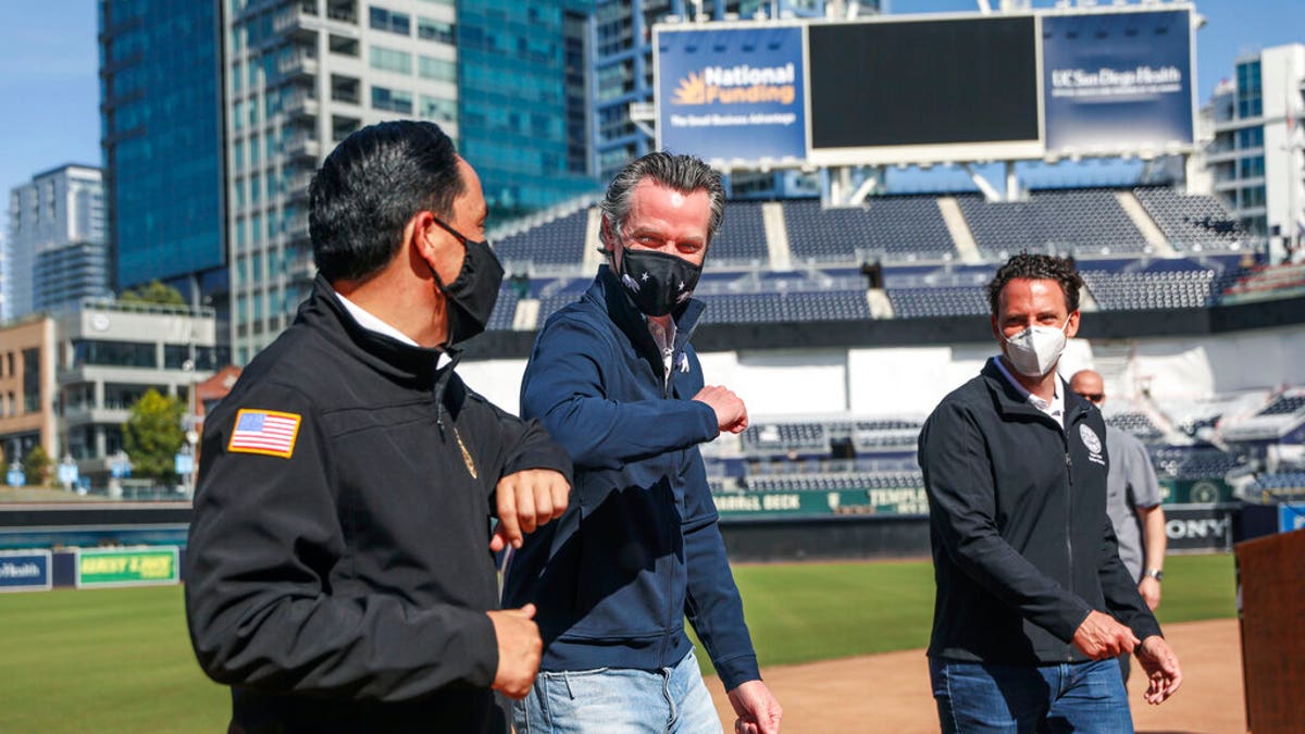 FILE: California Governor Gavin Newsom, center, bumps elbows with San Diego Mayor Todd Gloria after a news conference at Petco Park, which will host a vaccination site in a parking lot next to the ballpark in San Diego. 