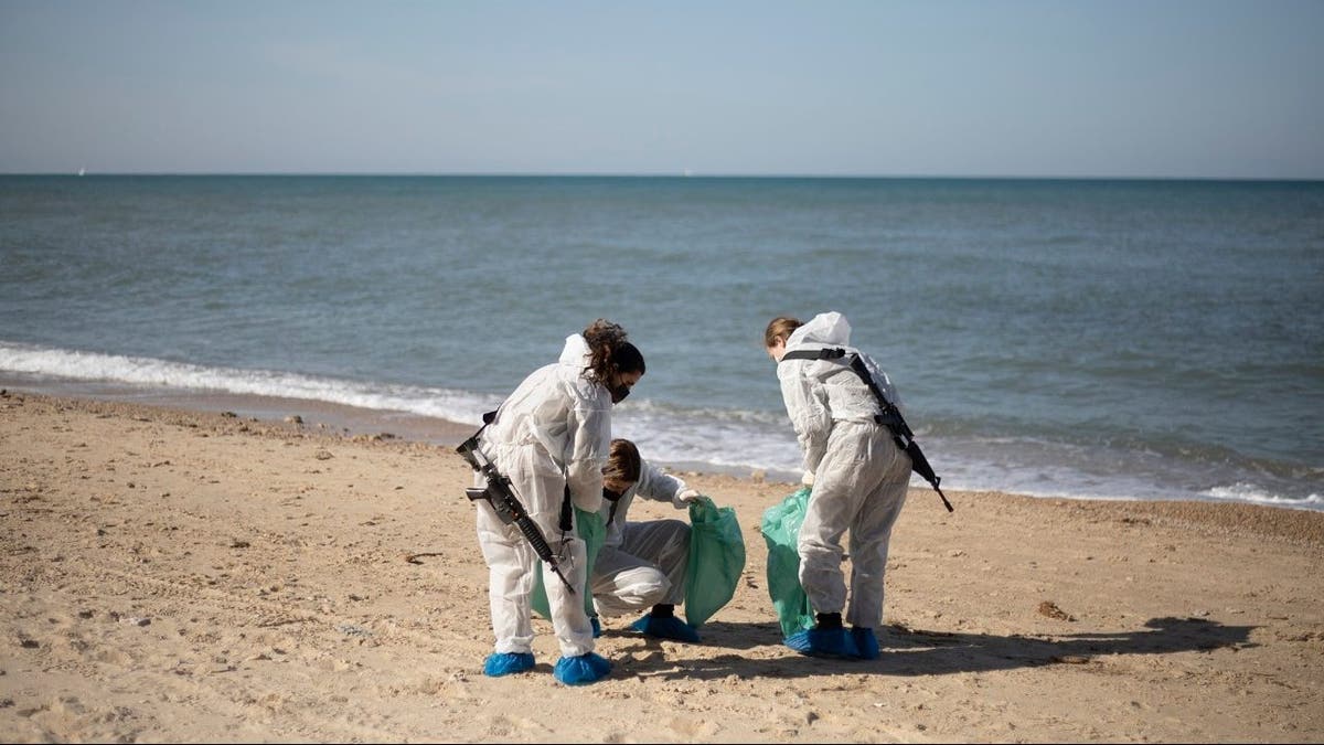Israeli soldiers wearing protective suits clean tar from a beach after an oil spill in the Mediterranean Sea in Sharon Beach Nature Reserve, near Gaash, Israel, Monday, Feb. 22, 2021. (AP Photo/Ariel Schalit)