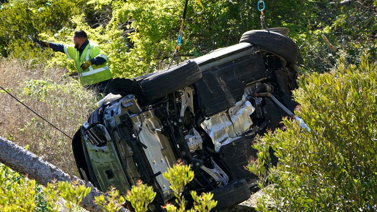 Workers move a vehicle on its side after a rollover accident involving golfer Tiger Woods on Feb. 23, 2021, in Rancho Palos Verdes, California. 