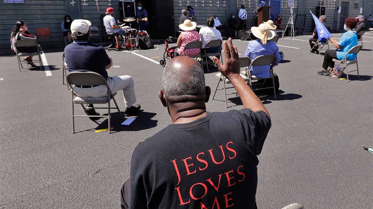FILE - In this Sunday, July 19, 2020 file photo, church parishioners sit apart socially distanced at a prayer vigil for racial justice at Immaculate Conception Catholic Church in Seattle. (AP Photo/Elaine Thompson)