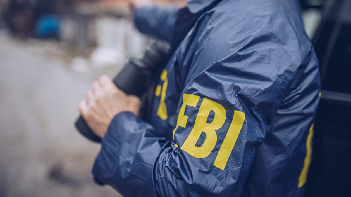 An FBI agent in blue jacket with yellow lettering