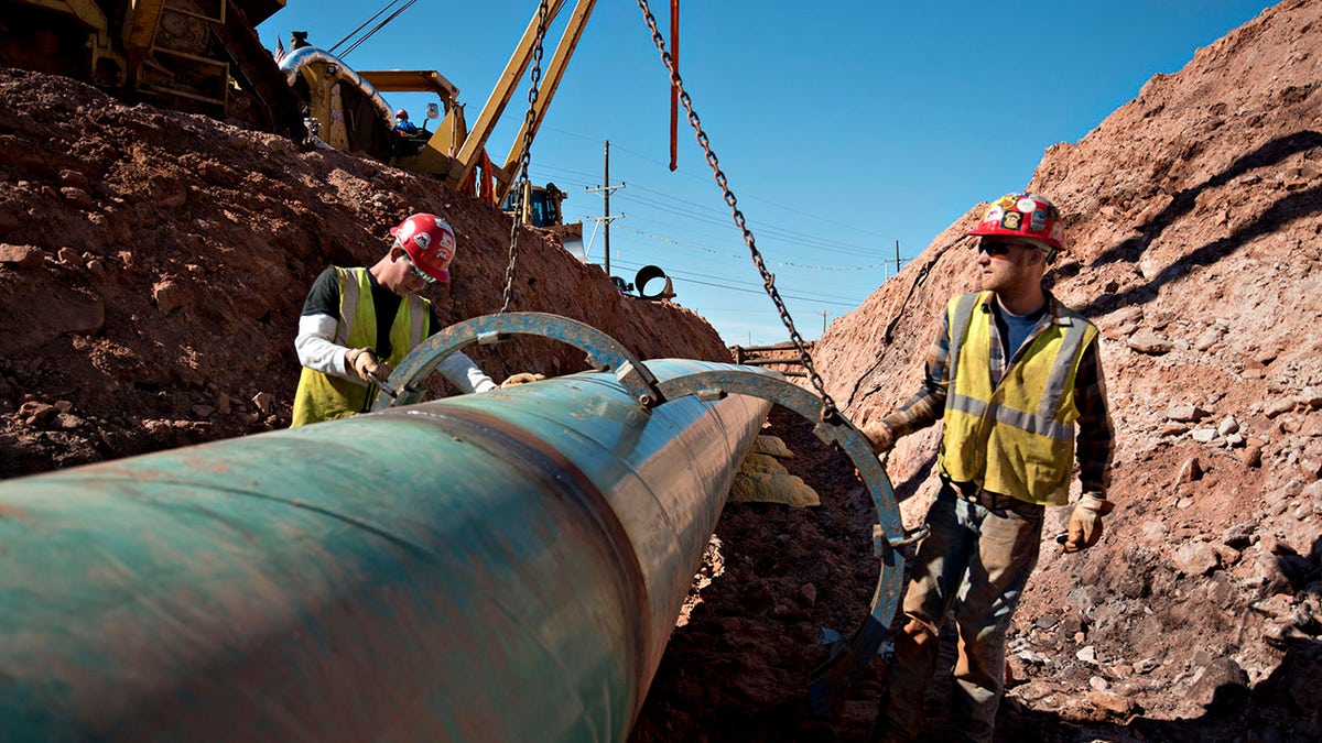 Workers remove a large clamp from a section of pipe during construction of the Gulf Coast Project pipeline in Prague, Oklahoma, on Monday, March 11, 2013. 