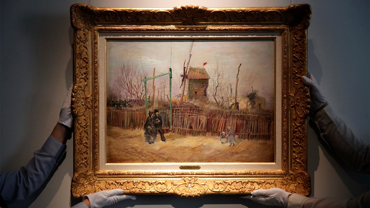 Sotheby's personnel display ??Scene de rue à Montmartre?? (Street scene in Montmartre), a painting by Dutch master Vincent van Gogh at Sotheby's auction house in Paris, Thursday, Feb. 25, 2021.? (AP Photo/Christophe Ena)