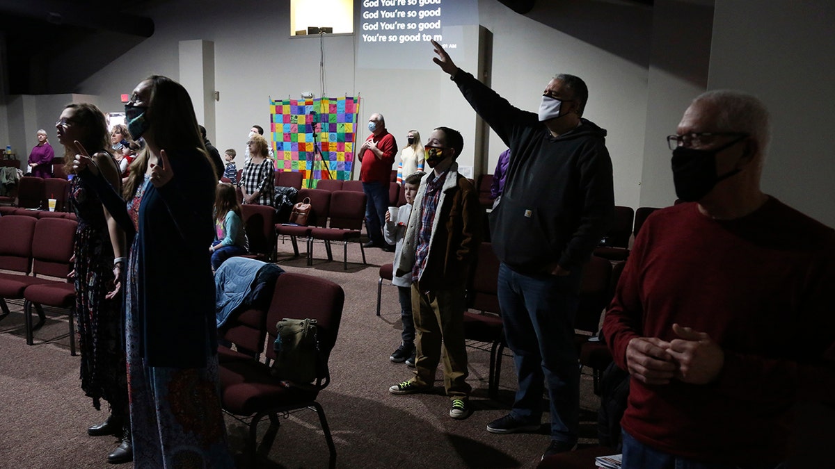 Travis Lowe, second from right, pastor of Crossroads Church in Bluefield, W.Va., raises his arm during services Sunday Jan. 23, 2021. Lowe, who has expressed concern over the divisiveness of American politics, believes collaboration by churches will help heal his town and the country. (AP Photo/Jessie Wardarski)