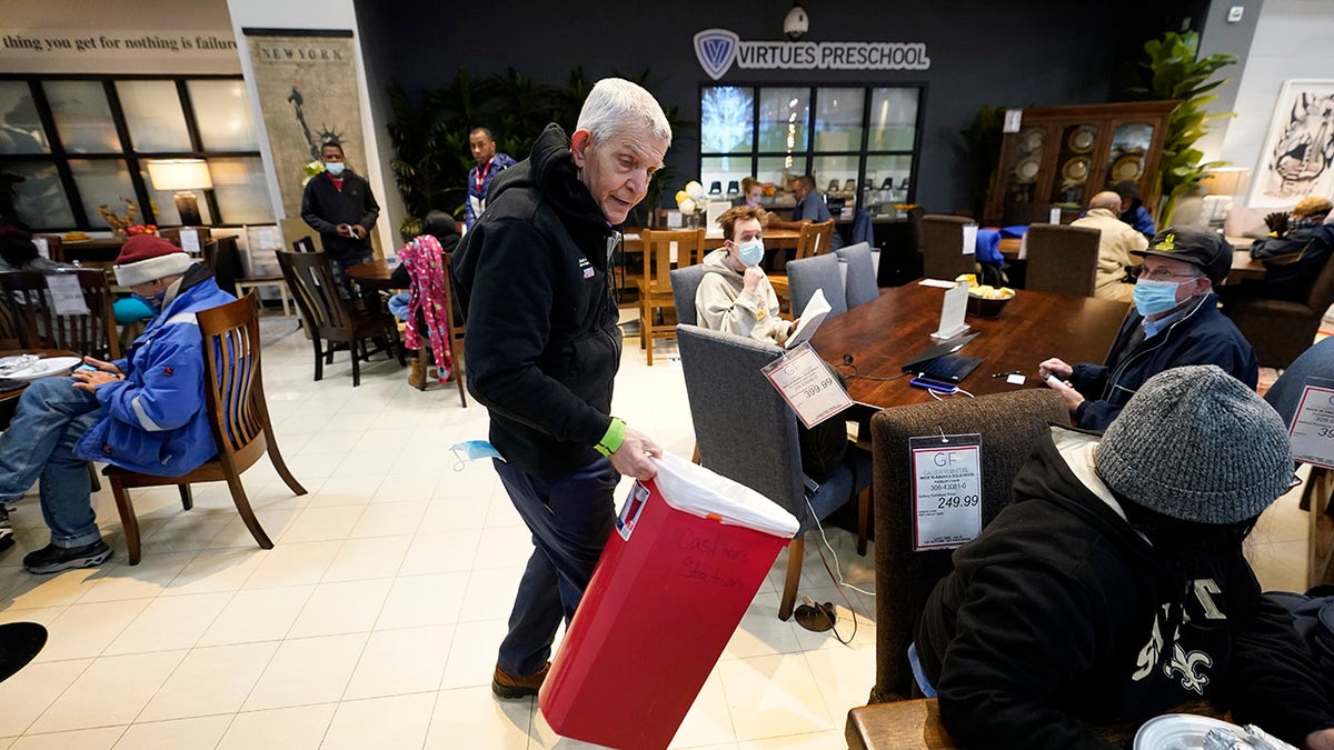 Owner Jim McIngvale collects trash inside his Gallery Furniture store which opened as a shelter Wednesday, Feb. 17, 2021, in Houston. (AP Photo/David J. Phillip)