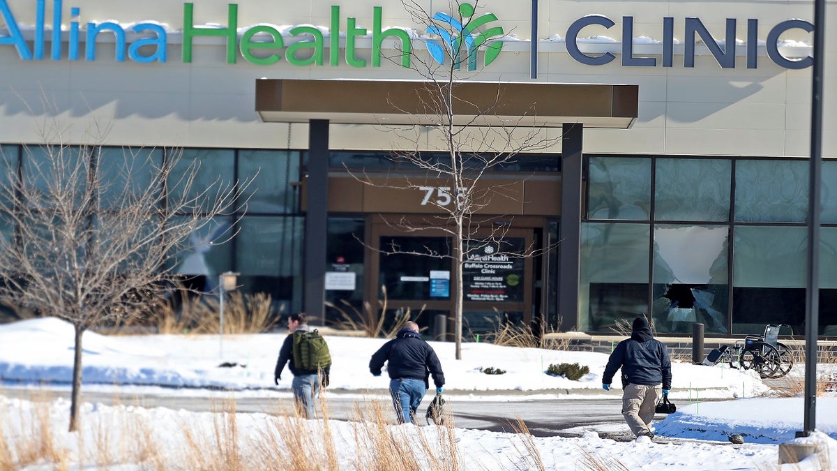 Law enforcement personnel walk toward the Allina Health clinic on Tuesday following the shooting there. (AP/Star Tribune)