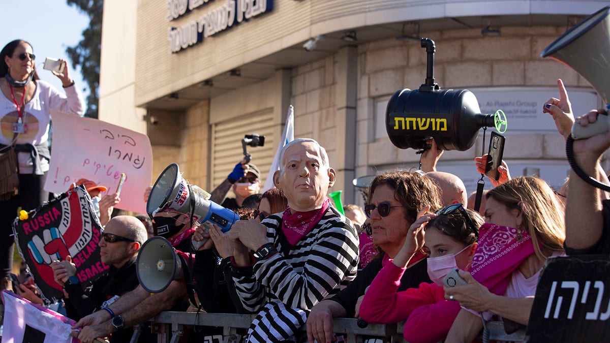 Protesters, including one wearing a mask depicting Israeli Prime Minister Benjamin Netanyahu, gather outside the District Court during a hearing in his corruption trial, in Jerusalem, Monday, Feb. 8, 2021. (AP Photo/Maya Alleruzzo)