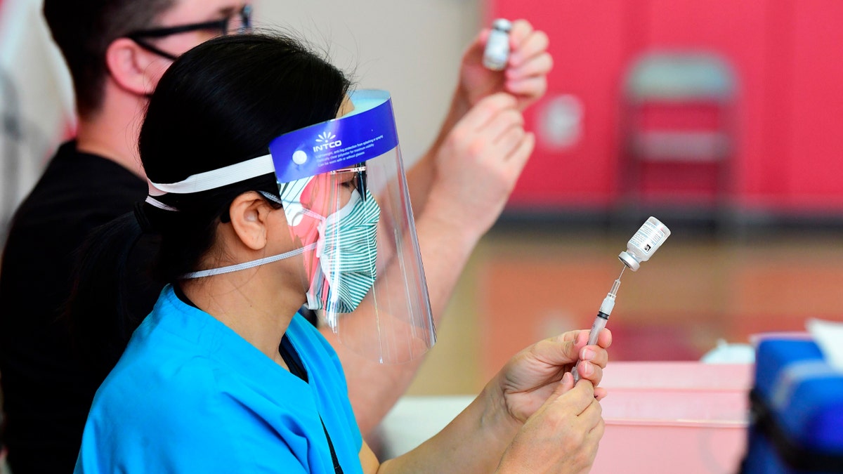 Registered nurses help transfer the Moderna COVID-19 vaccine from a bottle into a syringe ready for vaccination at the Corona High School gymnasium in the Riverside County city of Corona, California on January 15, 2021, a day after California began offering the coronavirus vaccine to residents 65 and older. (Photo by Frederic J. BROWN / AFP) (Photo by FREDERIC J. BROWN/AFP via Getty Images)