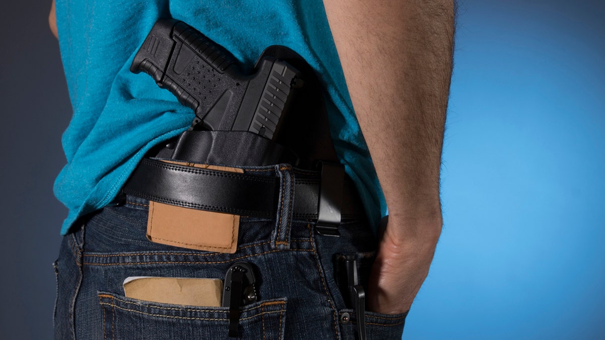 man displaying hip-holstered gun 