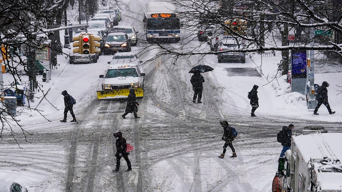 Pedestrians cross roads as snow falls Thursday in the Queens borough of New York City (AP)