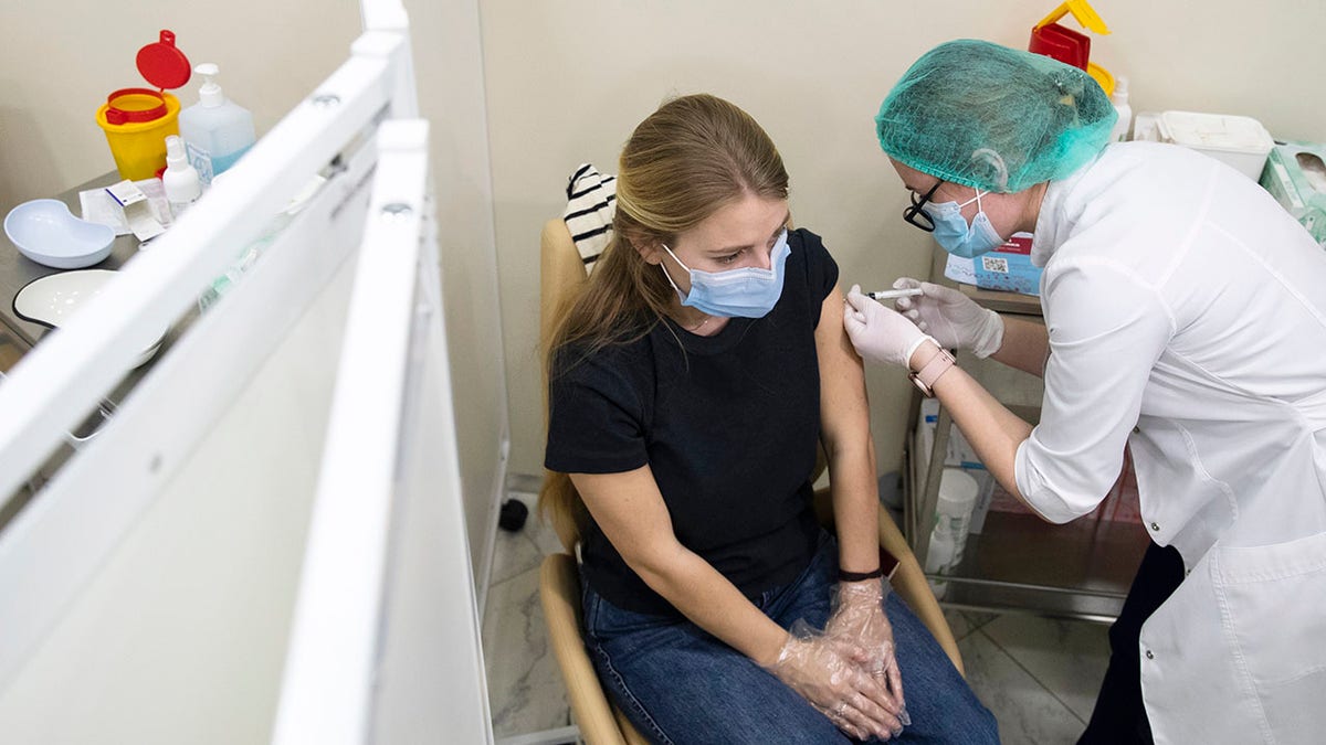 A Russian medical worker, right, administers a shot of Russia's Sputnik V coronavirus vaccine to a patient in a vaccination center in Moscow, Russia, Wednesday, Jan. 20, 2021.