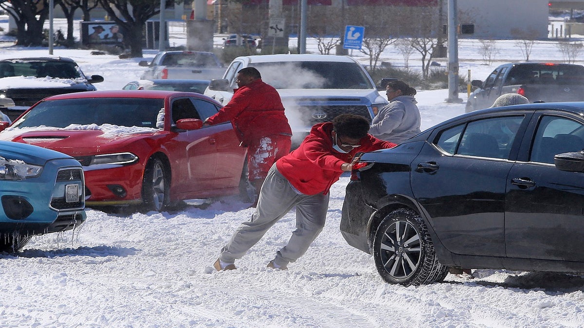 People push a car free after spinning out in the snow Monday in Waco, Texas. (AP/Waco Tribune-Herald)