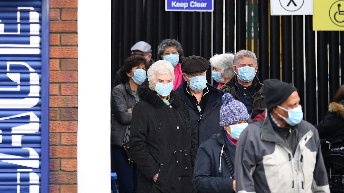 People wait in a queue to receive a vaccination against Covid-19 at a temporary centre set up at Selhurst Park football stadium in Croyden, south London (Photo by JUSTIN TALLIS/AFP via Getty Images)