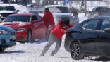People push a car free after spinning out in the snow Monday, Feb. 15, 2021 in Waco, Texas. A winter storm that brought snow, ice and plunging temperatures across the southern Plains and caused a power emergency in Texas stretched its frigid fingers down to the Gulf Coast.  (Jerry Larson/Waco Tribune-Herald via AP)