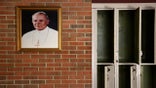 A portrait of St. John Paul II hangs beside a row of empty lockers in the main hallway of Quigley Catholic High School in Baden, Pa., in June 2020. (AP)
