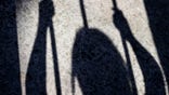 Shadow of female prisoner inside a prison cell projected on the ground. Women in captivity concept.