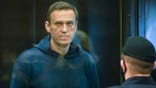 In this handout photo provided by Moscow City Court Russian opposition leader Alexei Navalny stands in the cage during a hearing to a motion from the Russian prison service to convert the suspended sentence of Navalny from the 2014 criminal conviction into a real prison term in the Moscow City Court in Moscow, Russia, Tuesday, Feb. 2, 2021. (Moscow City Court via AP)