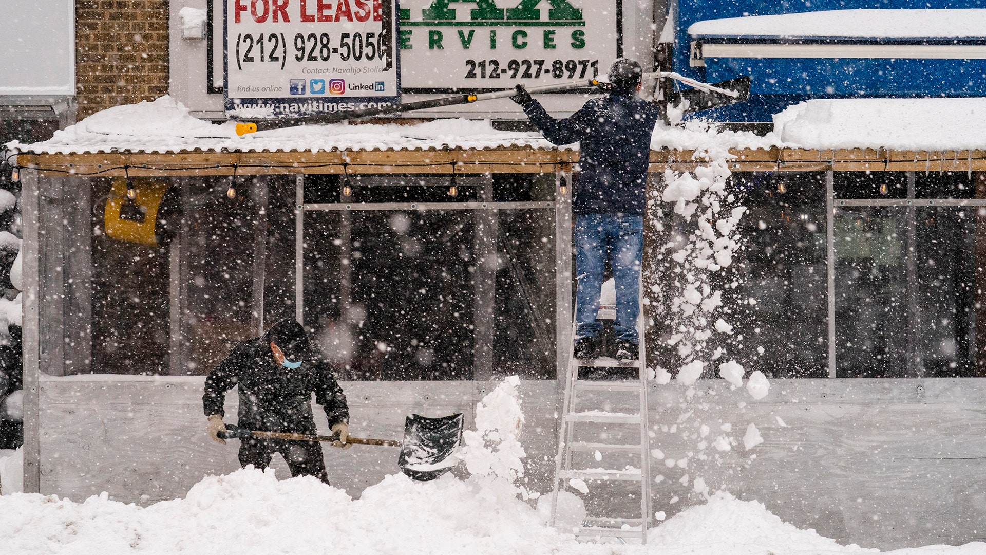 Workers clear snow away from an outdoor dining space erected due to COVID-19 restrictions, Monday, Feb. 1, 2021, in the Manhattan borough of New York. (AP Photo/John Minchillo)