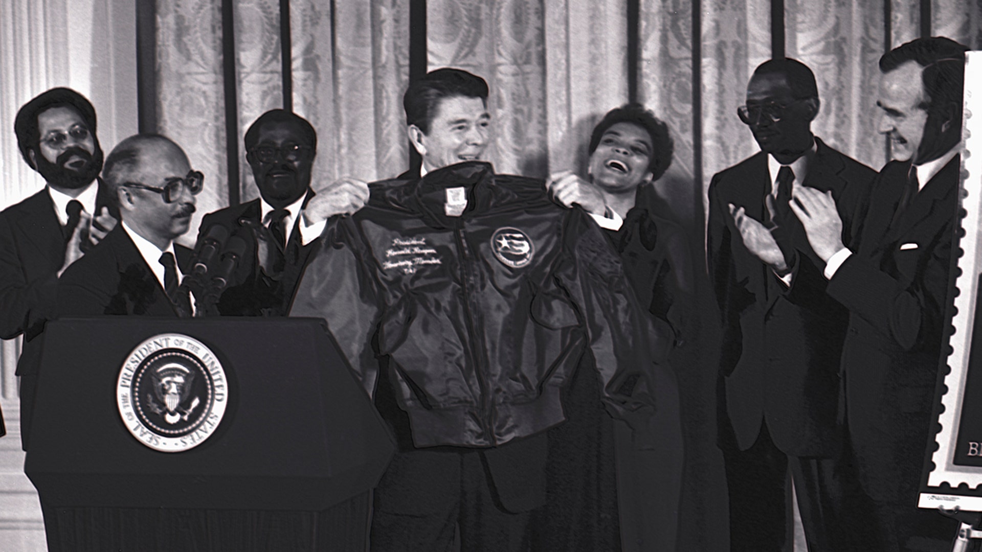 President Ronald Reagan is presented with a flight jacket by Lt. Colonel (Retired) Charles McGee, president of the Tuskegee Airmen Association, making Reagan an honorary member of the TAI, Washington, D.C., Feb. 2, 1984.